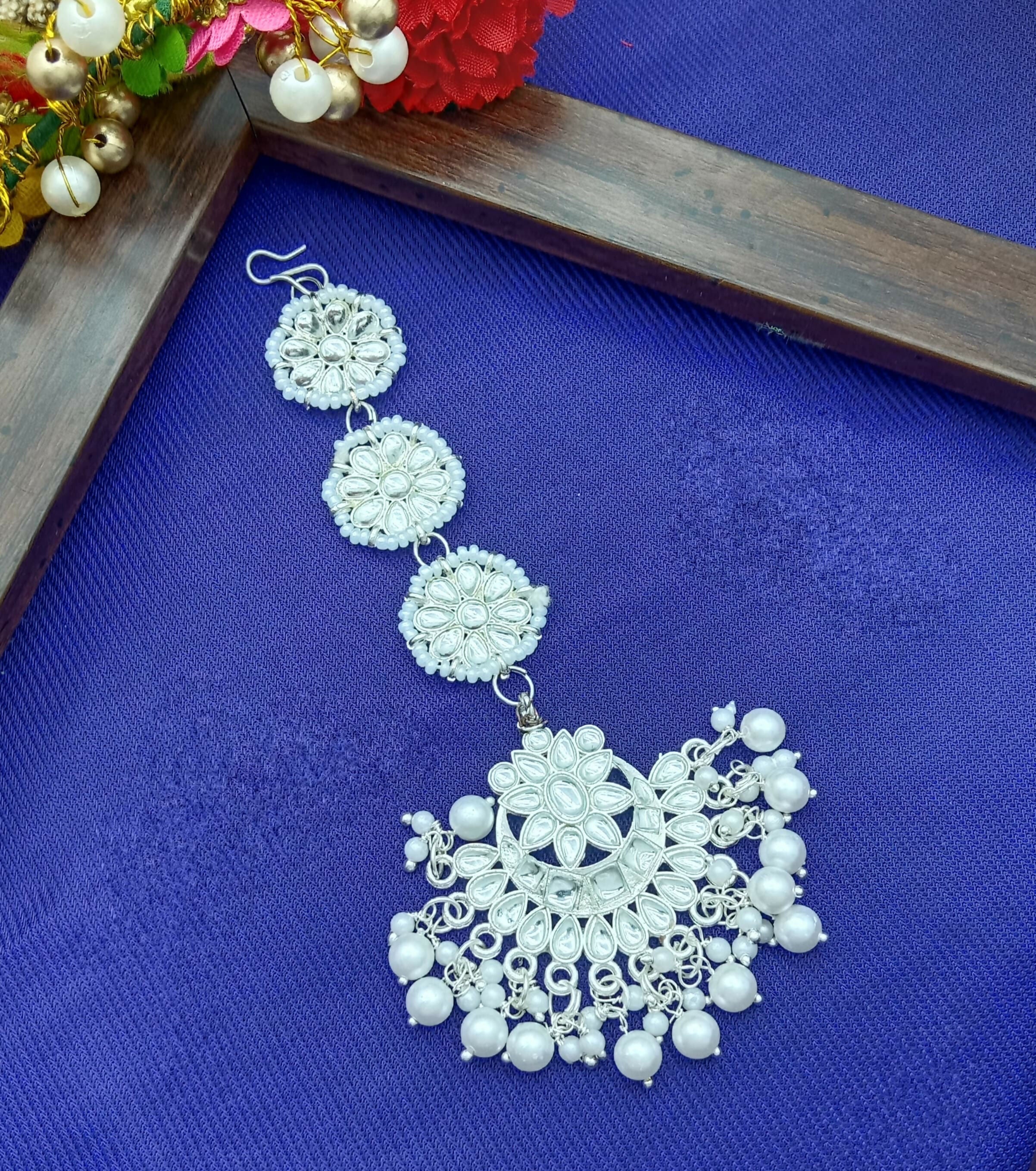 Enhance your ethnic look with this elegant White Gold Plated Kundan Maang Tika, designed to add timeless charm and grace to your traditional attire. Crafted with precision, this beautiful piece features sparkling artificial stones and delicate bead detail